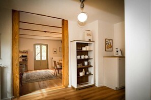 Ein Zimmer mit Holzboden, einem weißen Schrank, einem Regal mit Küchenutensilien und einer Tür zu einem anderen Raum.