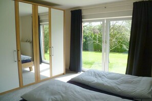 Ein Schlafzimmer mit einem Bett, einem Kleiderschrank und einer Glastür zu einem Garten.