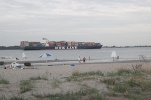 Ein Containerschiff mit Containern mit der Aufschrift 'NYK LINE' liegt in einem Hafen festgemacht.