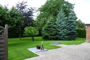 Ein gepflegter Garten mit Kiesweg, hölzernem Tor und einem großen Nadelbaum.