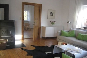 Ein Wohnzimmer mit einer Couch, einem Couchtisch, einem Kamin, einem weißen Schrank und einer Tür zu einem anderen Raum.