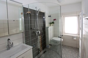 Un baño moderno con cabina de ducha de vidrio, inodoro y lavamanos.