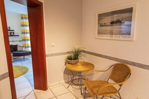 A small room with a wicker table and chairs, a potted plant, and a framed picture on the wall. - Sunflower, terrace and Moselle view (Cochem)