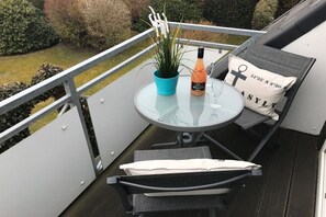A balcony with a glass table, a bottle, and a plant. - Holiday apartment with 2 bedrooms (Westerland)