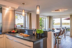 Eine moderne Küche mit einer zentralen Kochinsel, großen Fenstern und einem Essbereich mit Sitzgelegenheiten im Freien.