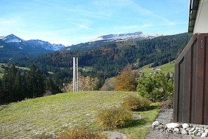 A mountainous landscape with a building featuring a wooden exterior and a stone pathway. - Holiday apartment with 2 bedrooms (Riezlern)