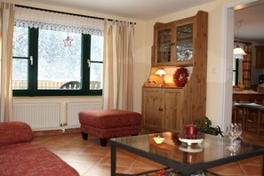 Ein gemütliches Wohnzimmer mit Kamin, Glastisch und Holzschrank.