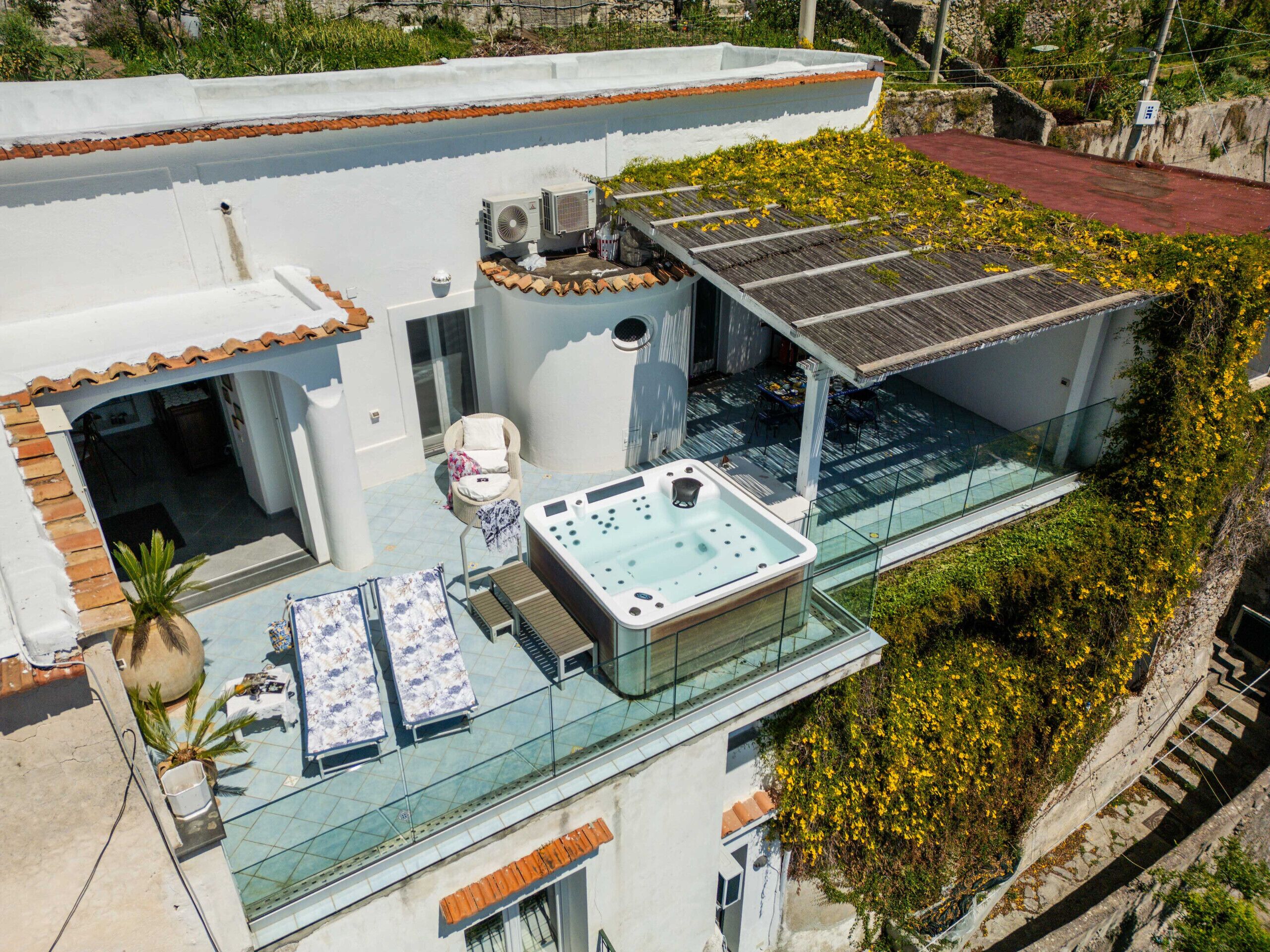 Une terrasse sur le toit avec un jacuzzi, des sièges extérieurs et un espace clos par des parois de verre.