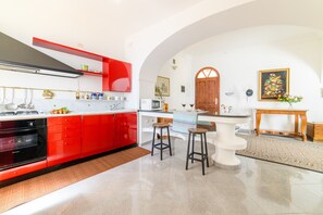 Eine Küche mit roten Schränken, einer weißen Arbeitsplatte und einem Holzespeisetisch mit zwei Hocker.