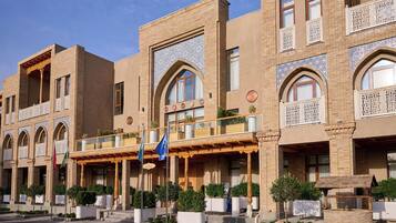 Um hotel de vários andares com arquitetura tradicional, apresentando janelas em arco e detalhes em tijolo decorativo.