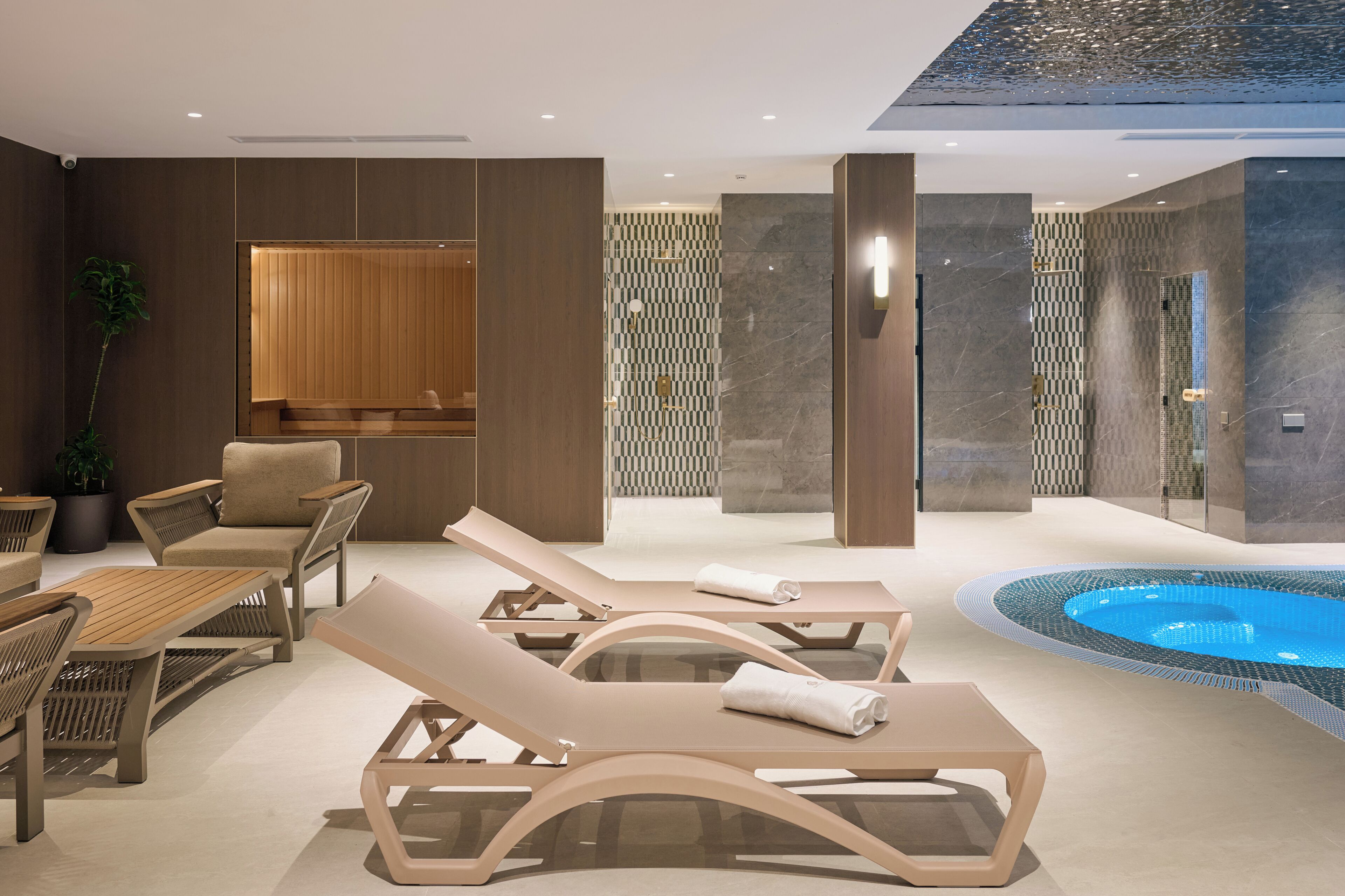 Uma área de spa moderna com espreguiçadeiras, banheira de hidromassagem e um espaço de estar com assentos de madeira.