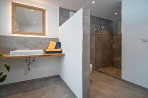 Ein modernes Badezimmer mit Waschbecken, Spiegel und Dusche.