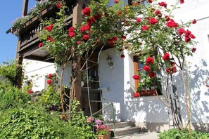 Ein weißes Gebäude mit einem hölzernen Balkon und roten Blumen.