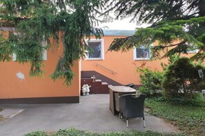 Ein Außenbereich mit Tisch und Stühlen, einer Treppe und einem Gebäude mit orangenen Wänden.