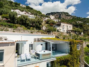 Une propriété située sur une colline, avec une maison moderne dotée d’un balcon en verre, d’une piscine et offrant une vue sur le paysage environnant.
