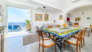 A dining area with a large table, chairs, and a view of the sea. - Estate4home - Villa Lettieri (Praiano)