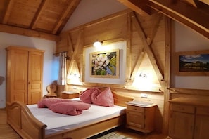 Ein Schlafzimmer mit Holzrahmen, ausgestattet mit einem Bett, zwei Nachttischen, einer Kommode und einem Bild an der Wand.