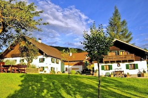 Ein traditionelles Chalet mit einem geneigten Dach, einer Holzterrasse und einem gepflegten Rasen.