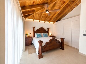 Ein Schlafzimmer mit Holzboden, einem Bett mit Kopfteil, Nachttischen und einem Kleiderschrank.