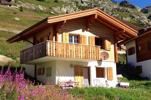 Ein Chalet mit Balkon, Satellitenschüssel und Bergblick.
