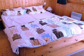 Ein Bett mit Tagesdecke, ein Nachttisch mit Lampe und ein an der Wand befestigter Heizkörper.