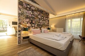 Ein Schlafzimmer mit zwei Betten, einer Wand mit Blumenmuster, Nachttischlampen und Blick ins Freie.