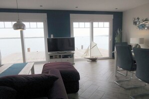 Ein Wohnzimmer mit Fernseher, einer Couch, einem Sessel und einem Modell eines Segelboots.