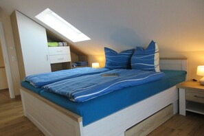 Ein Schlafzimmer mit Bett, Dachfenster, Nachttisch und Kleiderschrank.