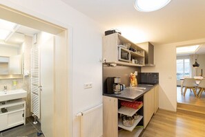 Cocina compacta con microondas integrado, cafetera y armarios de almacenamiento.
