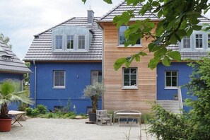 Eine Reihe von Häusern mit markanten blauen und hölzernen Fassaden, einem gepflasterten Innenhof und Außenplätzen.