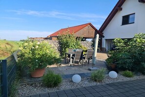 Eine Terrasse mit Gartenmöbeln, einer Steinmauer und einem hölzernen, auf einen Stall gestalteten Gebäude.