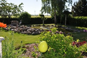 Ein Garten mit Teich, Steinen und einer Vogelstatue.