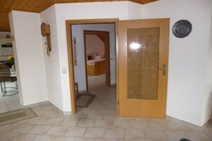 Ein Zimmer mit Holztür, einem kleinen Schreibtisch und einem Stuhl.