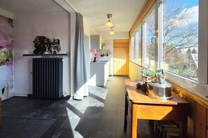 Eine moderne Küche mit großem Fenster, Heizkörper und Holztisch mit Wasserkocher.