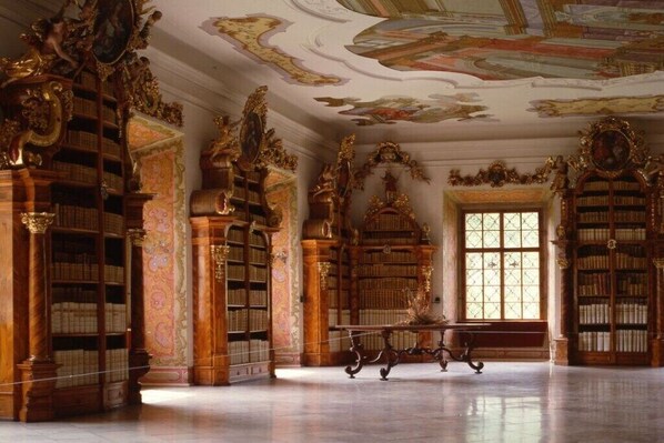 Eine prächtige Bibliothek mit aufwendigen Holzschnitzereien, hohen Bücherregalen und einem Marmorboden.