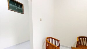 A room with white walls, a tiled floor, two wooden chairs, and a wooden table.