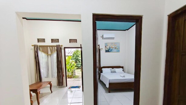 A room with a bed, a bench, and a door leading to a balcony.