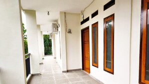 A corridor with tiled flooring, wooden doors, and a white wall.