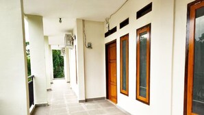A corridor with tiled flooring, wooden doors, and windows with wooden frames.