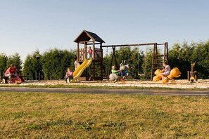 A playground with a slide, swings, and a climbing structure. - Holiday room with 1 bedroom (Märkische Heide OT Biebersdorf)