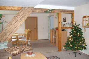 Ein gemütliches Wohnzimmer mit Holzboden, einem Essbereich mit Tisch und Stühlen, einem Weihnachtsbaum und einem Bücherregal.