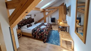 Un dormitorio con cama, escritorio, silla, televisor y espejo.