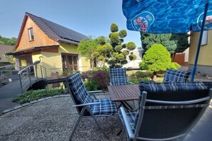 A patio area with outdoor seating, a small bridge, and a building with a sloped roof.