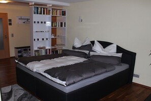 Un dormitorio moderno con una cama grande, una estantería y un pequeño escritorio.