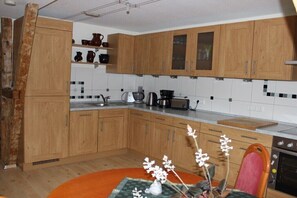 Una cocina con armarios de madera, un lavabo, una estufa y un comedor con mesa y sillas.