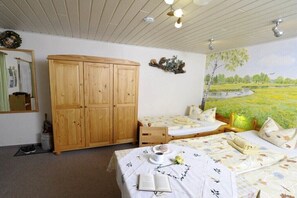 Ein Zimmer mit zwei Betten, einem Holzschrank, einem Spiegel und einem Landschaftsgemälde.