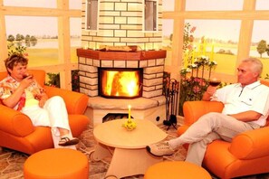 Ein Zimmer mit Kamin, orangefarbenen Sitzgelegenheiten und einem kleinen Tisch mit Kerze.