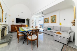 A spacious living area with a dining table, sofa, and fireplace. - Estate4home - Villa Lettieri (Praiano)