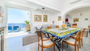 Un comedor con mesa, sillas y vista al mar.