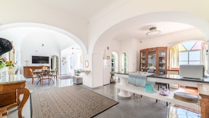 Amplia sala de estar con una mesa de comedor, un tapete grande y una cocina equipada con electrodomésticos modernos.